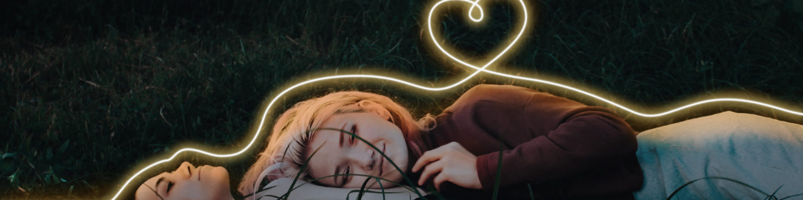 Två tjejer på en gräsmatta med ett ljusflöde som ett hjärta
